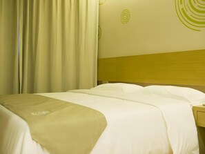 A hotel room with a bed, curtains, and a wall with a circular design. - Greentree Inn Nantong Qidong Lvsi Harbour Express Hotel (Nantong)