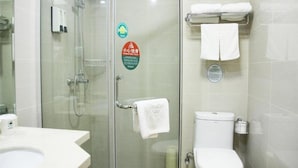 A bathroom with a glass-enclosed shower, a toilet, and a sink. There are towels hanging on a rack and a soap dispenser on the wall. - Greentree Inn Nantong Qidong Lvsi Harbour Express Hotel (Nantong)