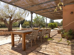 An outdoor patio with a pergola, stone flooring, and wicker furniture. - Villa in Muro With Swimming Pool (Muro)