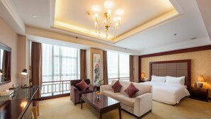A hotel room with a bed, two sofas, a coffee table, a desk, and a large window with curtains. - Rezen Hotel (Linyi)