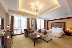 A hotel room with a bed, two sofas, a coffee table, a desk, and a large window with curtains. - Rezen Hotel (Linyi)