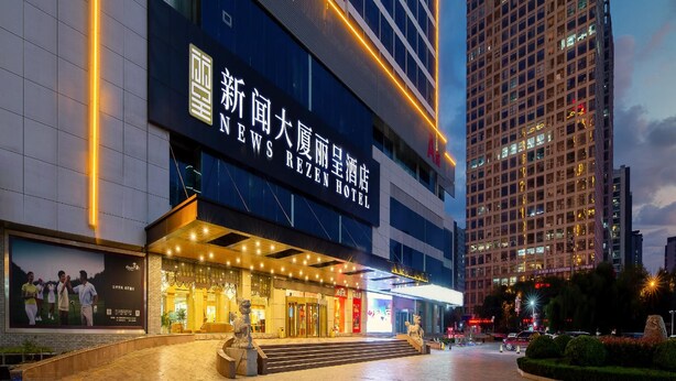 A hotel with a prominent sign, a well-lit entrance, and a large digital display. - Rezen Hotel (Linyi)