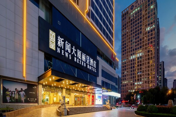 A hotel with a prominent sign, a well-lit entrance, and a large digital display. - Rezen Hotel (Linyi)