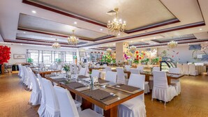 A banquet hall with multiple tables set for dining, chandeliers, and floral decorations. - Rezen Hotel (Linyi)