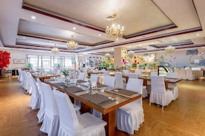 A banquet hall with multiple tables set for dining, chandeliers, and floral decorations. - Rezen Hotel (Linyi)