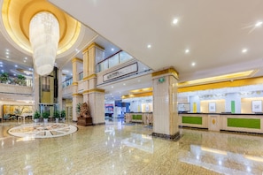 A multi-level lobby with a central atrium, marble flooring, and a grand chandelier. - Rezen Hotel (Linyi)