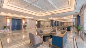 Eine großzügige Lobby mit hoher Decke, Marmorböden und modernen Sitzgelegenheiten.