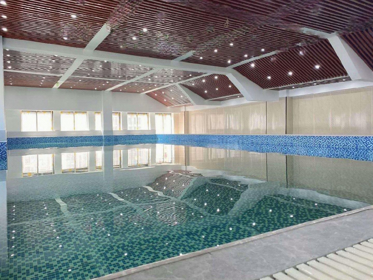 Une piscine intérieure offrant une vue dégagée sur le plafond et les murs, et dont le sol est carrelé.