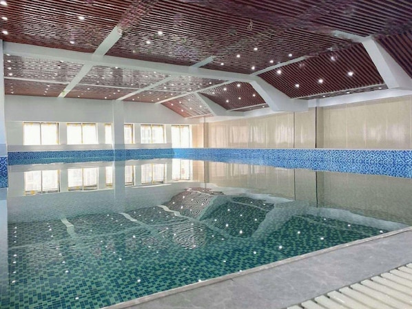 En indendørs swimmingpool med frit udsyn til lofter og vægge, samt et flisebelagt gulv.