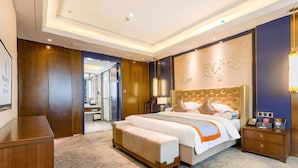 Ein Hotelzimmer mit einem großen Bett, einem Holztisch, einem Nachttisch und einem durch eine geöffnete Tür einsehbaren Badezimmer.