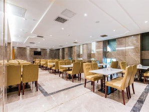 Une salle à manger d’hôtel avec des rangées de tables et de chaises, un sol en marbre et un design moderne au plafond.