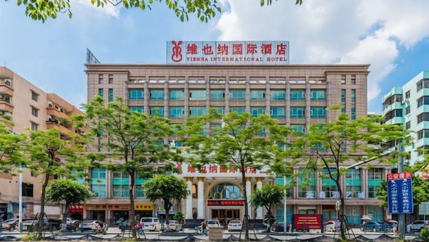 A multi-story building with a prominent sign for Vienna International Hotel. - Venus International Hotel Guangzhou Jiaokou Metro Station (Guangzhou)