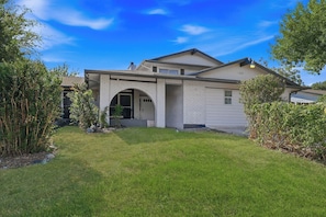 A two-story house with a brick facade, an arched entrance, and a well-maintained lawn.