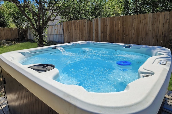 A hot tub with a wooden fence and trees in the background.