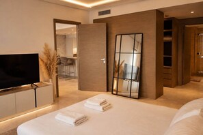 A modern hotel room with a large bed, a flat-screen TV, a mirror, and a walk-in closet. - New 1BR in Business Bay  Free Padel Court, Pool, Sauna (Dubai)
