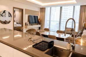 A modern kitchen with a central island, dining area, and a living space with a sofa and TV. - New 1BR in Business Bay  Free Padel Court, Pool, Sauna (Dubai)