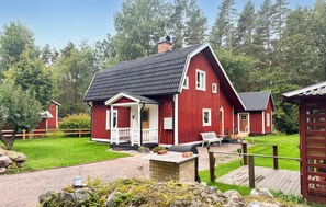Ein rotes Holzhaus mit Veranda, kleiner Terrasse und umzäunter Garten.
