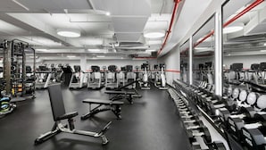 Un gimnasio con cintas de correr, bancos de pesas y mancuernas.