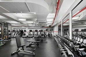 A gym with treadmills, weight benches, and dumbbells. - TWA Hotel (Jamaica)