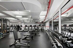Un gimnasio con cintas de correr, bancos de pesas y mancuernas.
