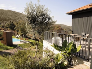 A residential outdoor area with a swimming pool, lounge chairs, and a fenced patio.