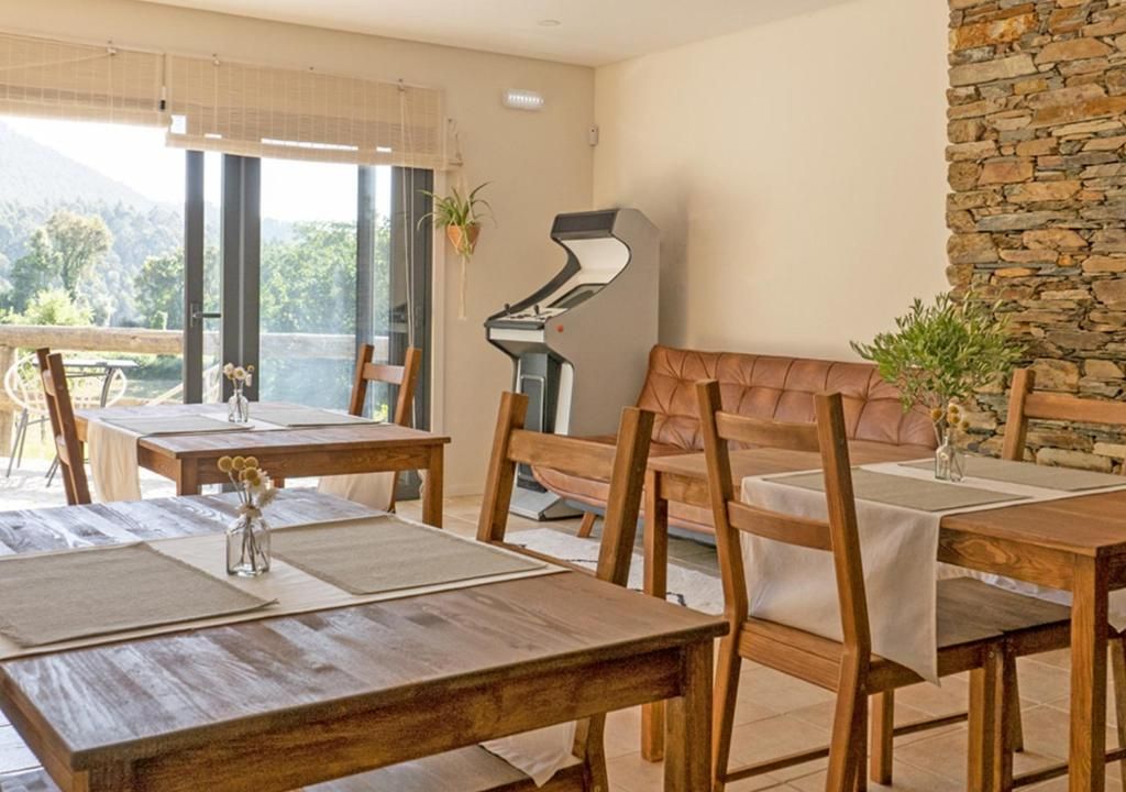 A dining area with wooden tables and chairs, a piano, and a stone wall.