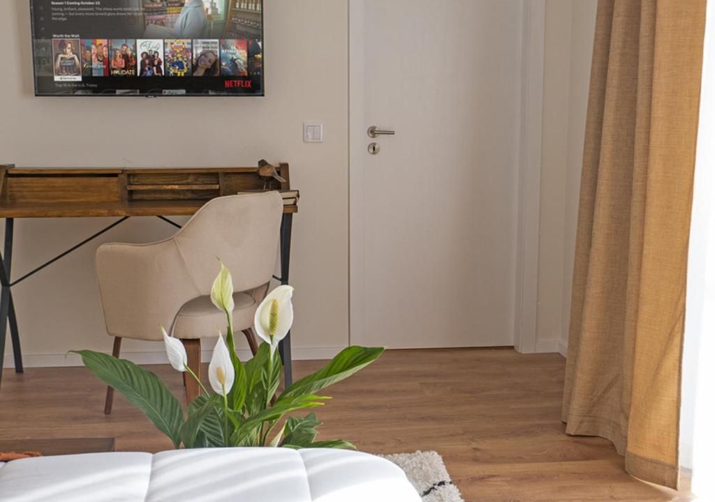 Habitación de hotel con cama, escritorio, silla y televisor empotrado en la pared mostrando una película.