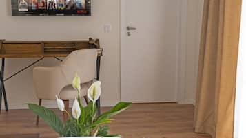 Habitación de hotel con cama, escritorio, silla y televisor empotrado en la pared mostrando una película.