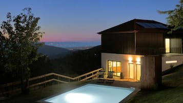 Una casa moderna con piscina, balcón y vistas del paisaje.