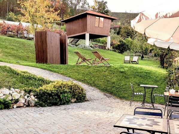 A patio area with a wooden deck, lounge chairs, and a small wooden structure.