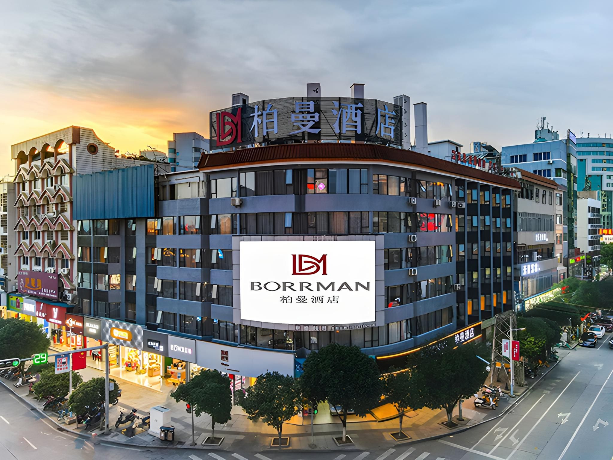 A multi-story building with a prominent Borman hotel sign, surrounded by other commercial buildings and a busy street.