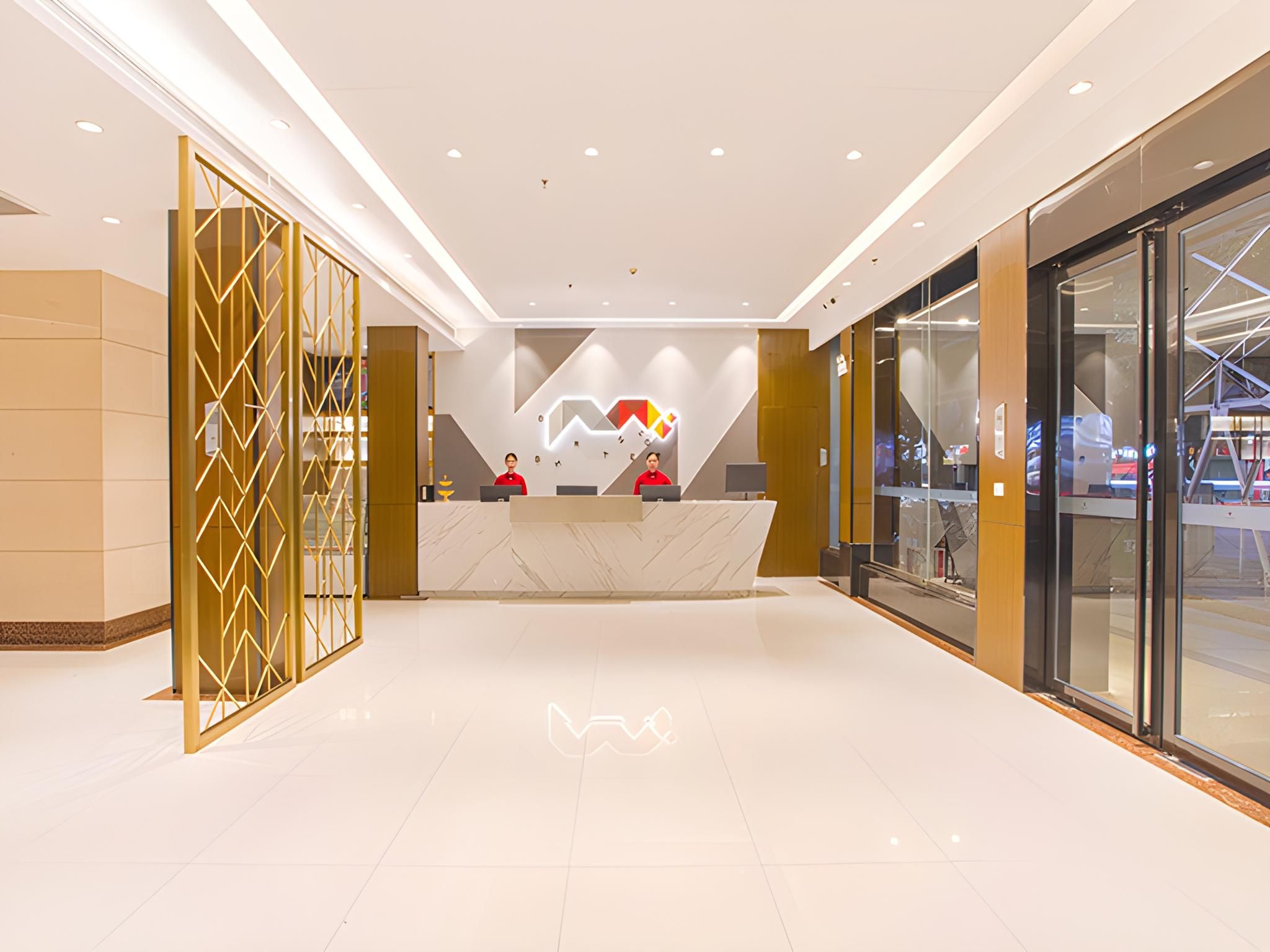 A modern reception area with a marble counter, glass doors, and a geometric wall design.