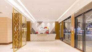 A modern reception area with a marble counter, glass doors, and a geometric wall design. - Borrman Hotel (Hezhou)