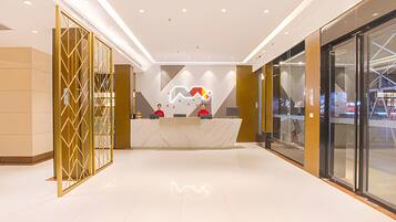 A modern reception area with a marble counter, glass doors, and a geometric wall design.