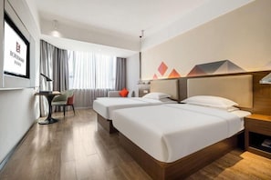 Hotellihuone, jossa on kaksi sänkyä, työpöytä ja tuoli.