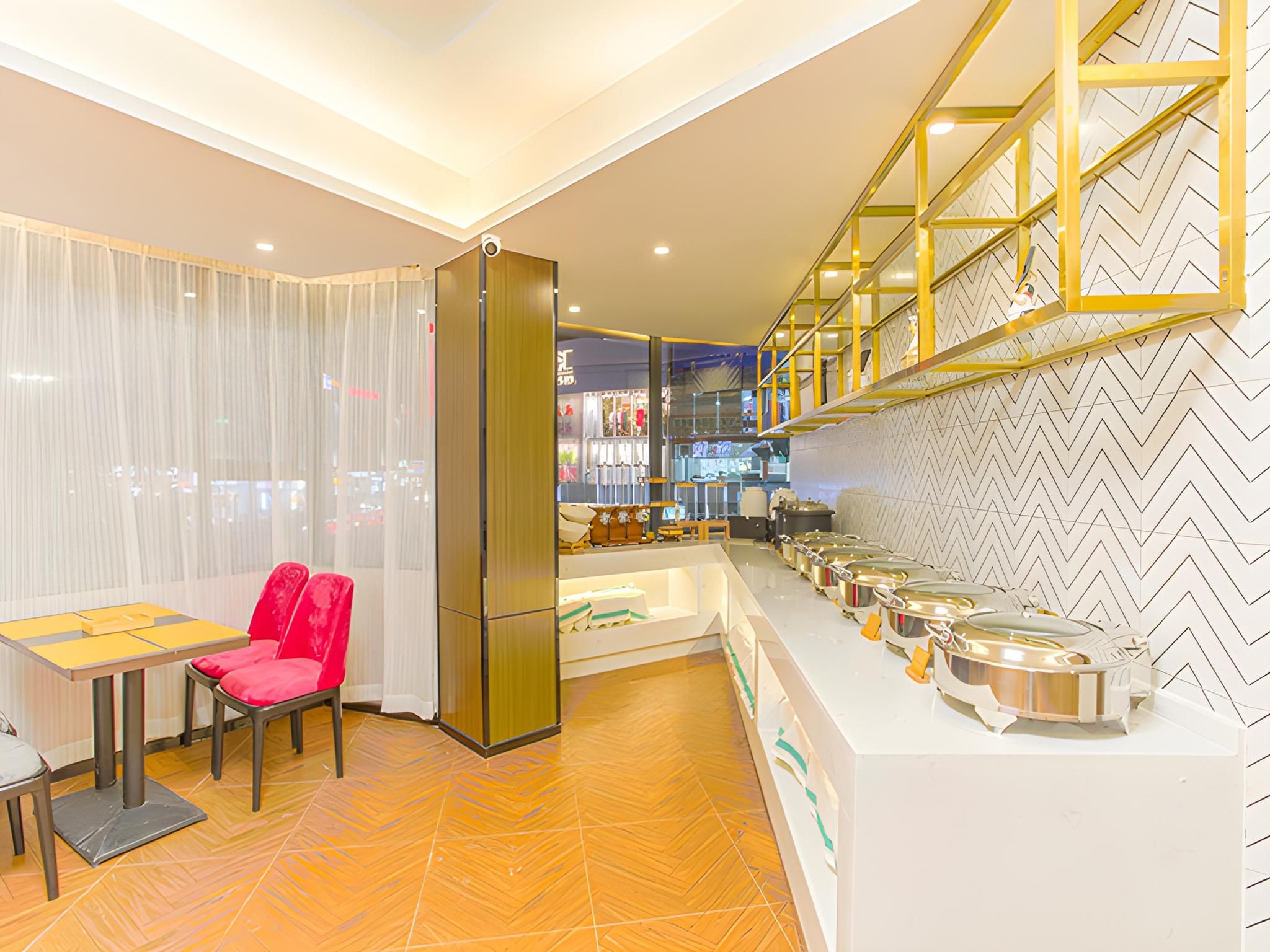 A modern kitchen with a buffet setup, a dining area with a table and chairs, and a herringbone patterned floor.