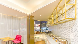 A modern kitchen with a buffet setup, a dining area with a table and chairs, and a herringbone patterned floor. - Borrman Hotel (Hezhou)