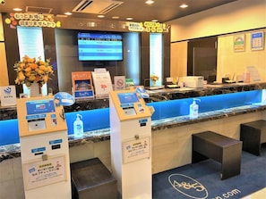 Un espace d’accueil d’hôtel doté d’un écran numérique, d’un comptoir bleu et d’un panneau indiquant une réduction de 5 %.