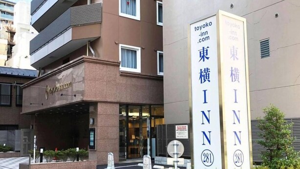 En bygning med et skilt for 'Toyoko Inn' og et stort, vertikalt skilt med navnet 'Toyoko Inn' og nummer '281'.