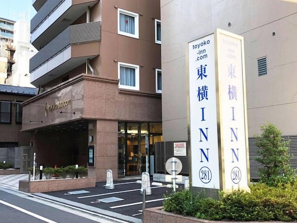 Un bâtiment sur lequel on peut voir une enseigne indiquant « Toyoko Inn » et une grande enseigne verticale portant le nom « Toyoko Inn » et le numéro « 281 ».