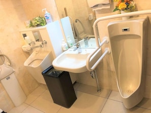 Des toilettes pour hommes, équipées d’un lavabo, d’un miroir, d’urinoirs et d’une poubelle.