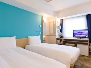 Une chambre d’hôtel avec deux lits, un bureau avec un ordinateur, une télévision et une fenêtre avec des rideaux.