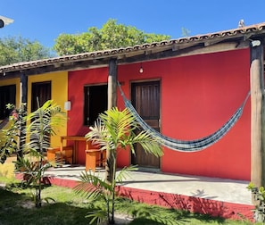 Un bâtiment rouge avec un porche, un hamac et un petit jardin.