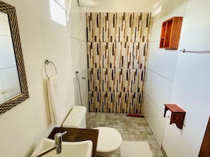 Une salle de bain équipée d’une douche, de toilettes, d’un lavabo et d’un miroir.