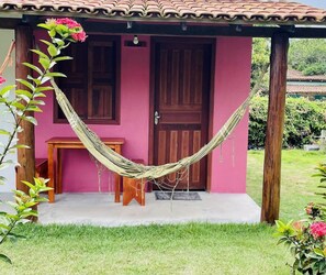 A pink building with a wooden door and a hammock. - Pousada Aquarela Caraiva (Porto Seguro)
