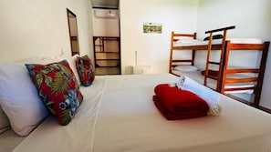 Une chambre d’hôtel avec un lit, un lit superposé, un miroir, une étagère et un petit tableau accroché au mur.