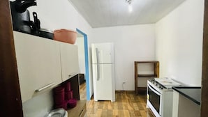 A compact kitchen with a refrigerator, stove, and wooden flooring. - Pousada Aquarela Caraiva (Porto Seguro)