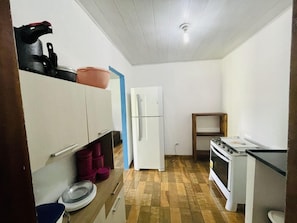 Une cuisine de taille réduite, équipée d’un réfrigérateur, d’une cuisinière et dotée d’un plancher en bois.