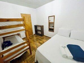 A room with a bunk bed, a single bed, a small table, and a mirror. - Pousada Aquarela Caraiva (Porto Seguro)