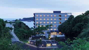 Ein mehrstöckiges Hotel mit modernem Design in der Nähe eines Gewässers und Blick auf die Küste.
